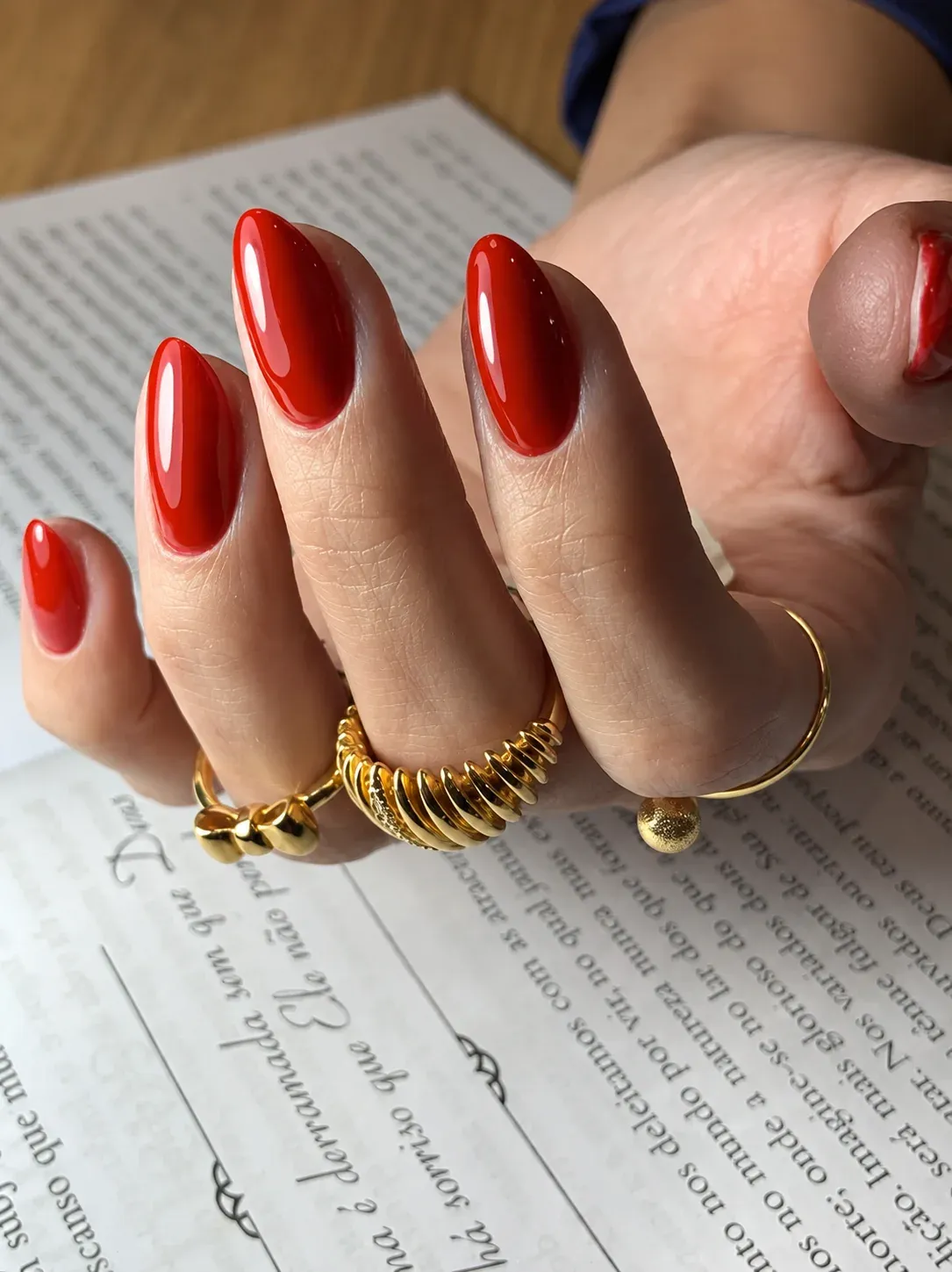 Unhas em esmalte vermelho com anéis dourados